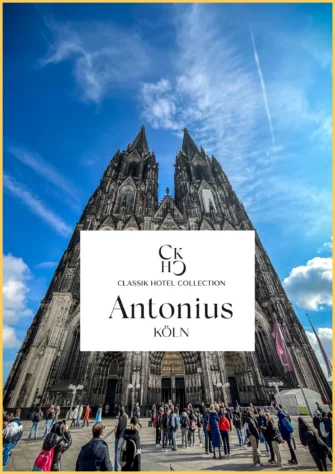 18 A large crowd stands in front of the Gothic-style Cologne Cathedral under a blue sky with clouds, perhaps gathering for a freewalk cologne tour. In the center, a white banner reads CKH5 Classik Hotel Collection Antonius Köln.
